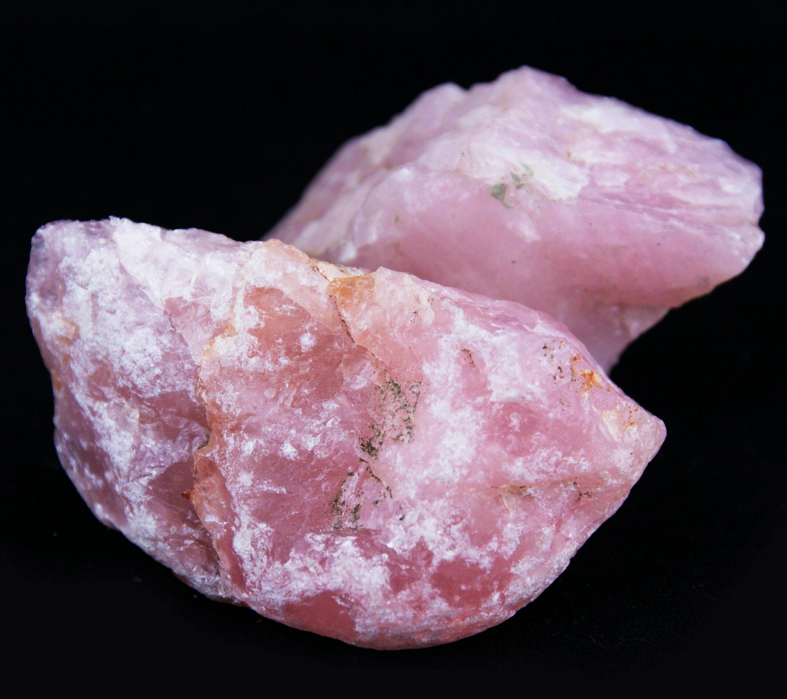 Cuarzo rosa natural en bruto con tonos suaves rosados sobre fondo oscuro